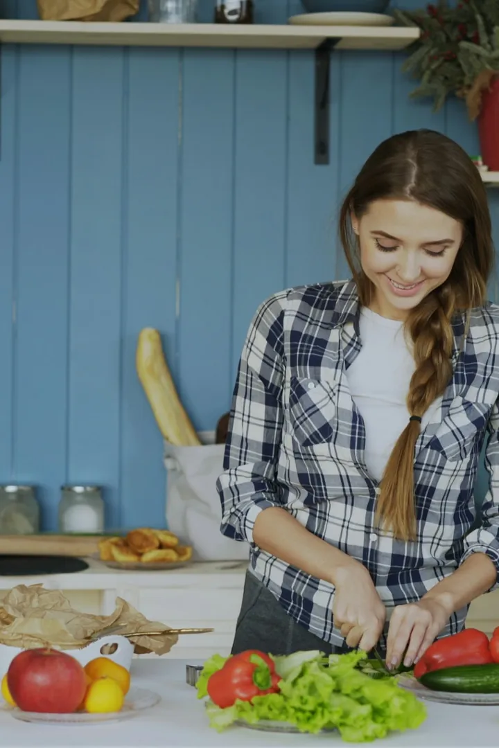 Imagen referencial: mujer picando verduras frescas en su cocina