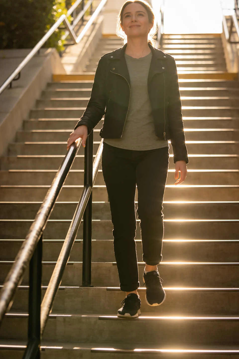 Imagen referencial: mujer bajando una escalera al sol, sonriendo